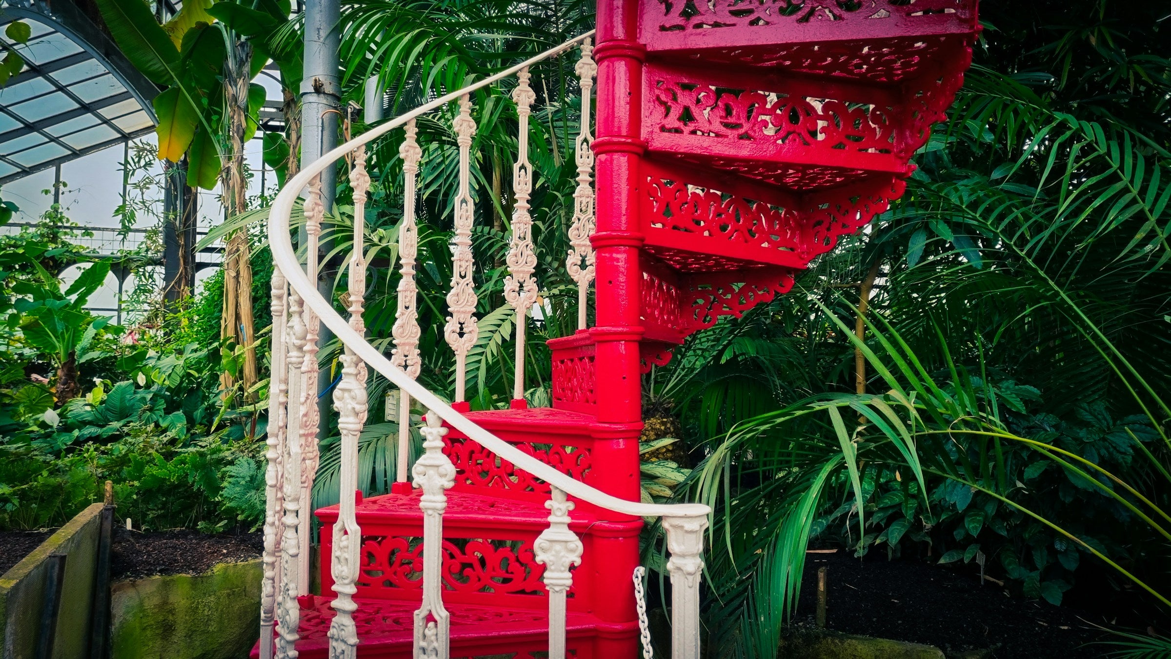 Twisting red stairs in greenhouse full of tropical plants